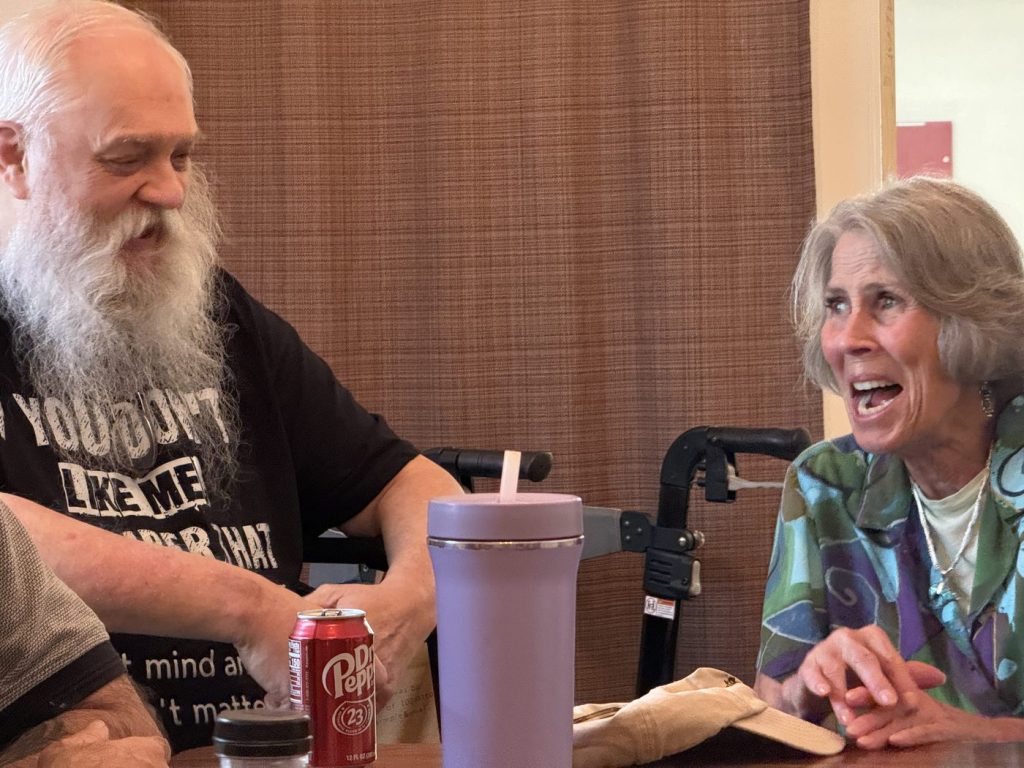 Two Shelter Home guests laughing together at a table